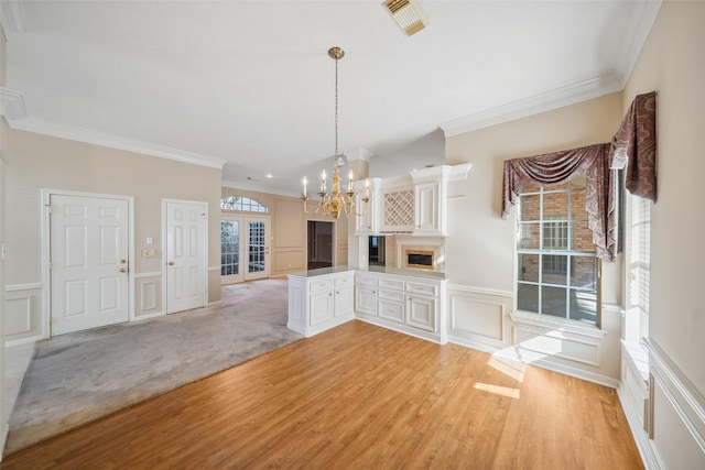 kitchen with a notable chandelier, a peninsula, a decorative wall, and light wood-style floors