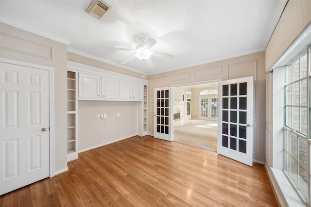 interior space featuring light wood finished floors, a closet, crown molding, visible vents, and french doors