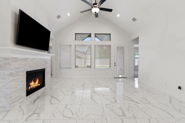 unfurnished living room featuring ceiling fan, a fireplace, high vaulted ceiling, marble finish floor, and a wealth of natural light