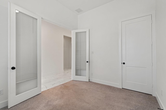 unfurnished bedroom with carpet floors, visible vents, marble finish floor, baseboards, and french doors