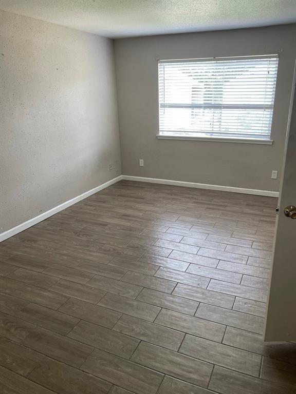 unfurnished room featuring a textured ceiling, baseboards, and dark wood finished floors