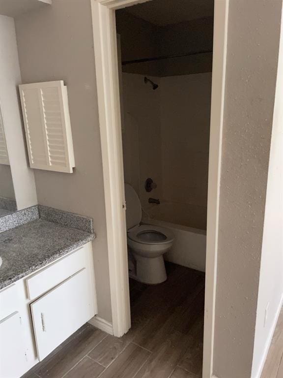 bathroom with toilet, tub / shower combination, wood finished floors, and vanity