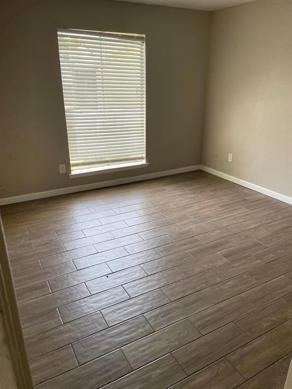 unfurnished room with dark wood-style floors and baseboards
