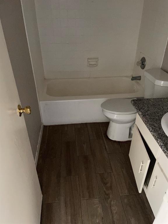 full bathroom with toilet, vanity, washtub / shower combination, and wood finished floors
