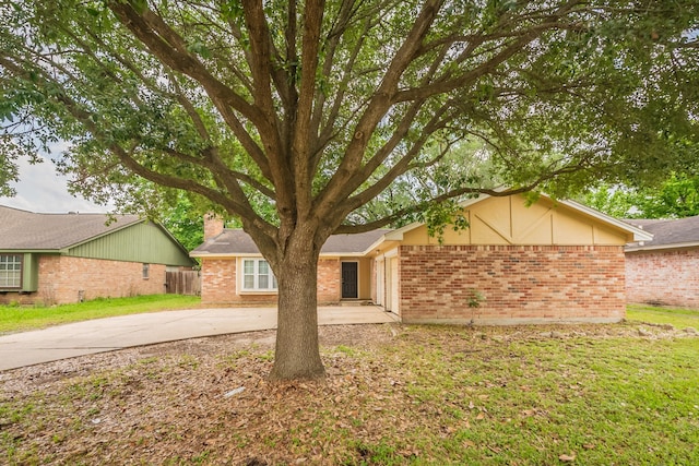 view of front of property with concrete driveway, fence, a front yard, and brick siding