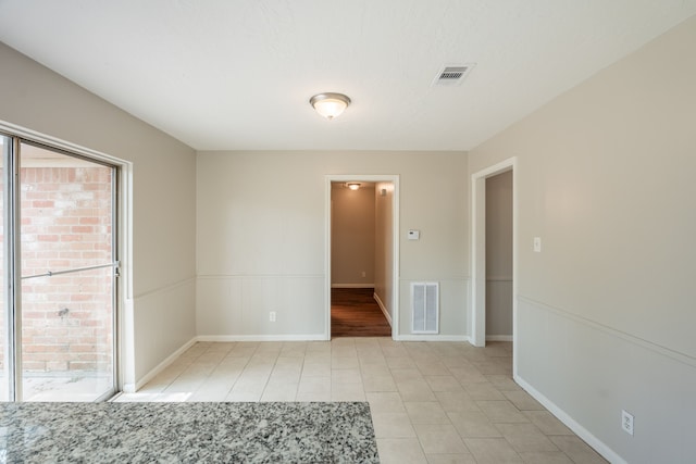 empty room with light tile patterned floors, visible vents, and baseboards