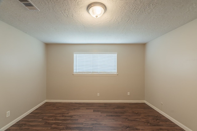 spare room with dark wood-style floors, baseboards, visible vents, and a textured ceiling