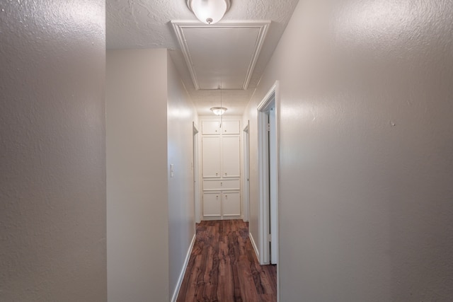 hallway featuring attic access, wood finished floors, and baseboards