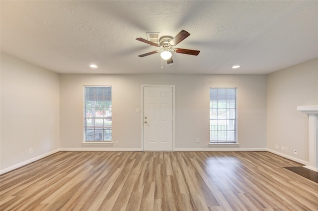 unfurnished room with light wood-style floors, a healthy amount of sunlight, a ceiling fan, and baseboards