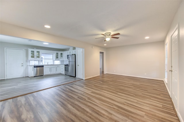 unfurnished living room featuring recessed lighting, a sink, baseboards, light wood-type flooring, and a ceiling fan