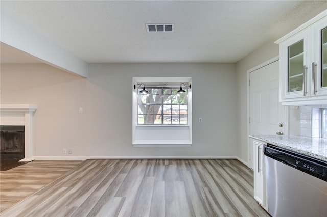 unfurnished living room featuring a fireplace with flush hearth, light wood-style floors, visible vents, and baseboards