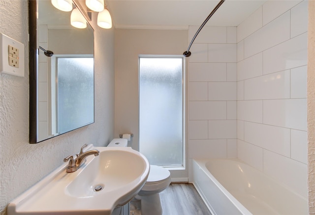 bathroom featuring a sink, toilet, ornamental molding, shower / bath combination, and wood finished floors