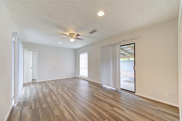 spare room with visible vents, wood finished floors, a ceiling fan, and plenty of natural light