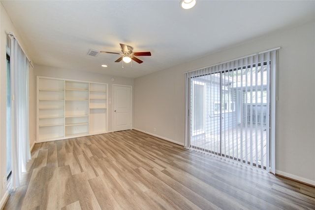 empty room with wood finished floors, visible vents, ceiling fan, and baseboards