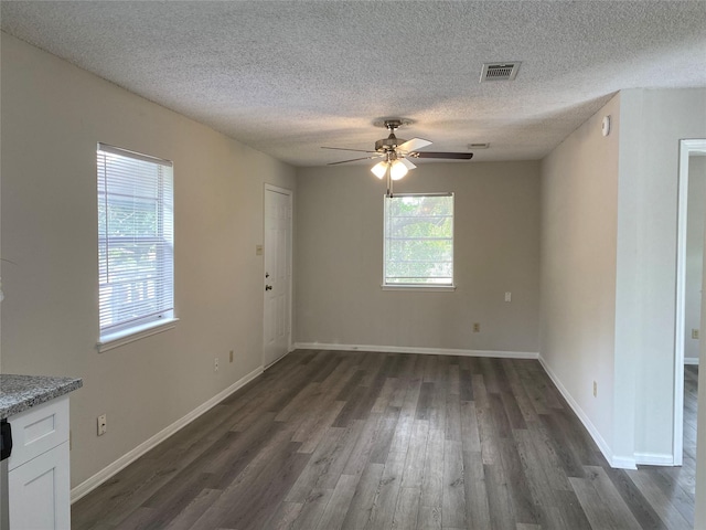 interior space with dark wood finished floors, visible vents, a ceiling fan, and a textured ceiling