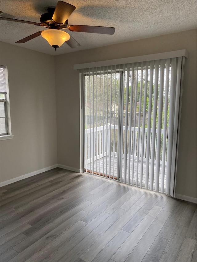 empty room featuring wood finished floors, plenty of natural light, a ceiling fan, and baseboards