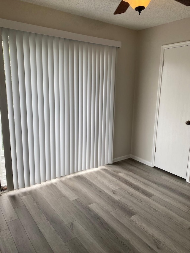 empty room with wood finished floors, a ceiling fan, baseboards, and radiator