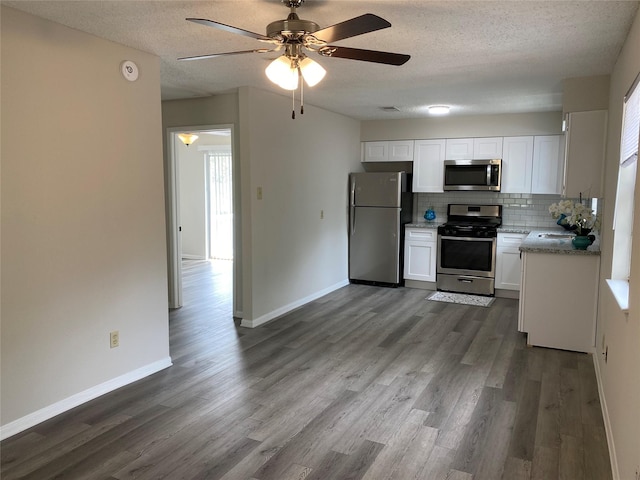 kitchen with decorative backsplash, ceiling fan, stainless steel appliances, and dark wood finished floors