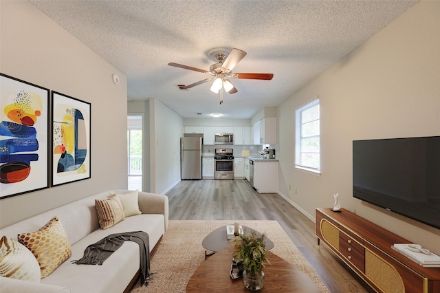 112 Begonia Ln, Highlands, TX 77562 - living area featuring light wood-style flooring, a textured ceiling, ceiling fan, and baseboards