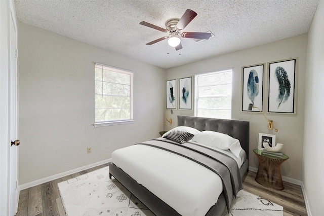 112 Begonia Ln, Highlands, TX 77562 - bedroom with wood finished floors, a textured ceiling, baseboards, and a ceiling fan