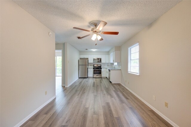 112 Begonia Ln, Highlands, TX 77562 - unfurnished living room featuring light wood-type flooring, ceiling fan, a textured ceiling, and a sink