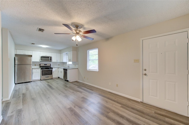112 Begonia Ln, Highlands, TX 77562 - kitchen featuring stainless steel appliances, white cabinetry, light wood-type flooring, light countertops, and a textured ceiling
