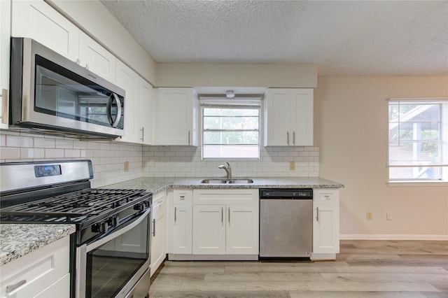 112 Begonia Ln, Highlands, TX 77562 - kitchen featuring stainless steel appliances, a sink, plenty of natural light, light wood-style floors, and a textured ceiling