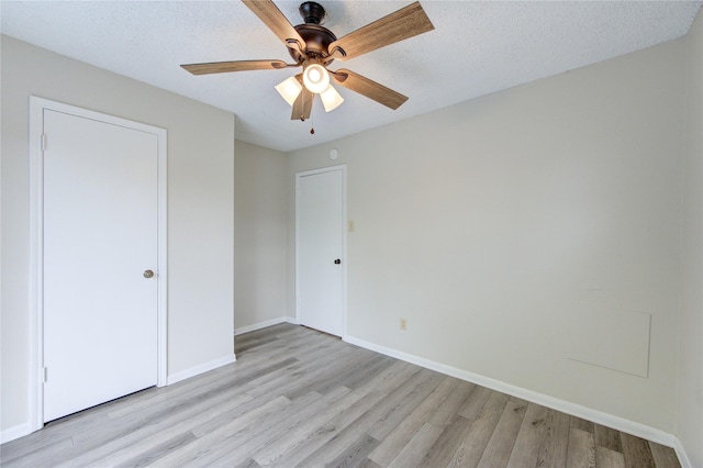 112 Begonia Ln, Highlands, TX 77562 - unfurnished bedroom with light wood-style floors, baseboards, a ceiling fan, and a textured ceiling