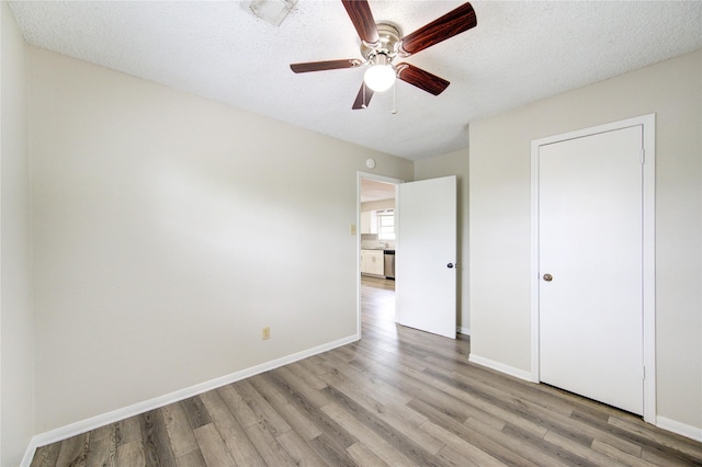 112 Begonia Ln, Highlands, TX 77562 - unfurnished bedroom featuring light wood-type flooring, baseboards, a textured ceiling, and a ceiling fan