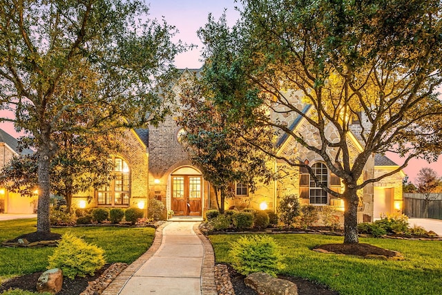 view of front of house with french doors, brick siding, stone siding, and a front yard