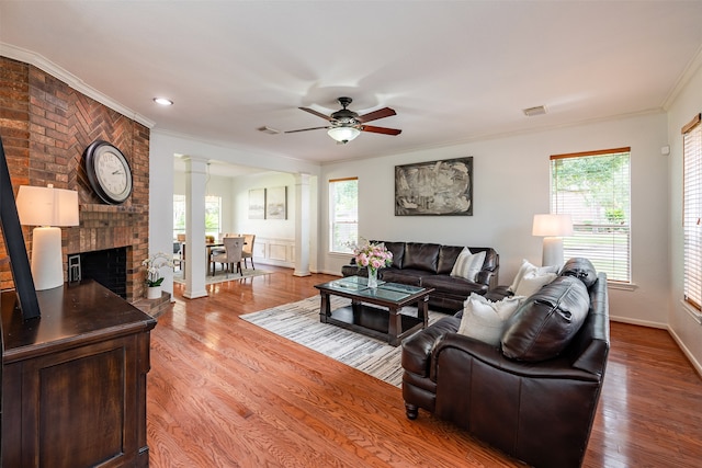 living area with ceiling fan, plenty of natural light, crown molding, and decorative columns