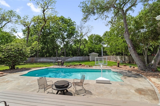 2215 Pecan Lake Dr, Richmond, TX 77406 - view of swimming pool featuring an outdoor fire pit, a shed, an outbuilding, view of wooded area, and a patio