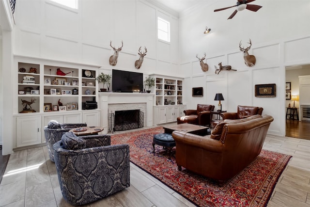 2215 Pecan Lake Dr, Richmond, TX 77406 - living room featuring a decorative wall, a ceiling fan, a high ceiling, ornamental molding, and a fireplace with flush hearth