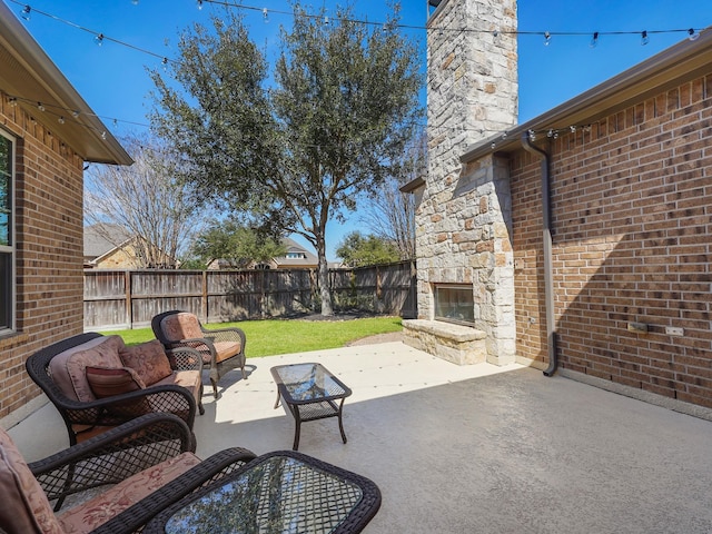 view of patio / terrace featuring an outdoor stone fireplace and a fenced backyard