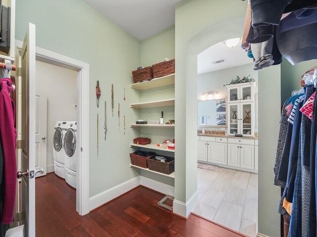 laundry room with visible vents, baseboards, washer and dryer, wood finished floors, and laundry area