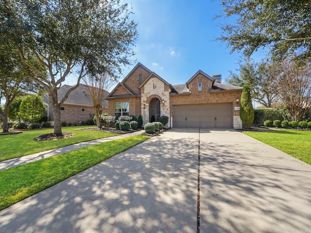 french country inspired facade featuring a chimney, driveway, stone siding, a front lawn, and an attached garage