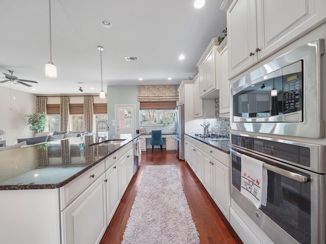 kitchen with a kitchen island with sink, white cabinetry, stainless steel appliances, and a sink