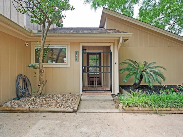 view of exterior entry featuring a shingled roof