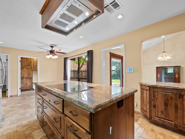 kitchen featuring visible vents, stone tile flooring, a kitchen island, black electric cooktop, and under cabinet range hood