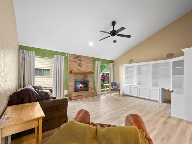 living area featuring visible vents, a fireplace, high vaulted ceiling, light wood-type flooring, and a ceiling fan
