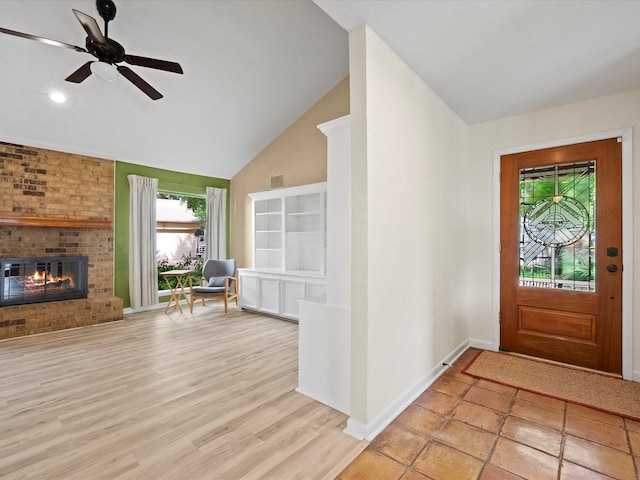 entrance foyer featuring visible vents, a fireplace, baseboards, high vaulted ceiling, and a ceiling fan