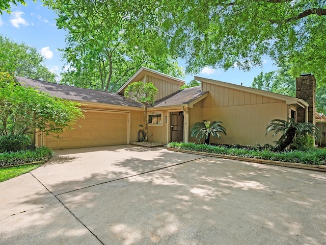 mid-century home with driveway, a chimney, and a garage
