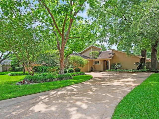 mid-century modern home featuring concrete driveway, an attached garage, and a front lawn