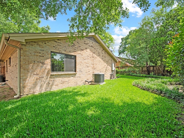 view of home's exterior with a lawn, central AC unit, fence, and brick siding
