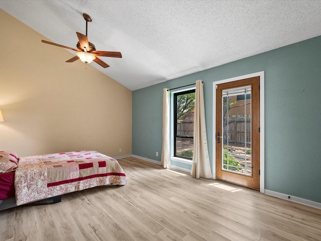 bedroom featuring lofted ceiling, wood finished floors, baseboards, access to outside, and a textured ceiling