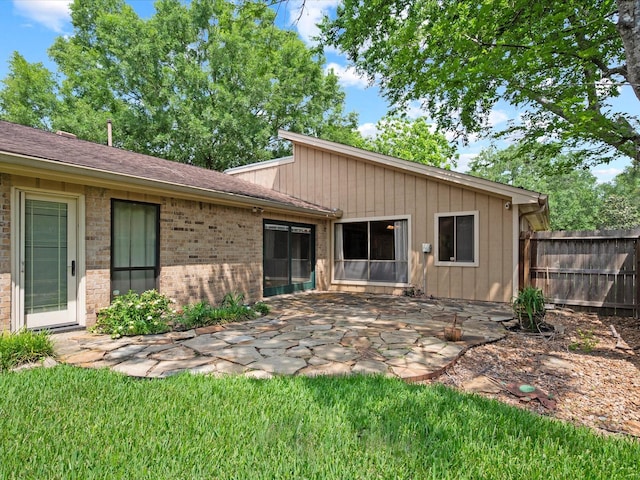 rear view of property with a patio, fence, and brick siding