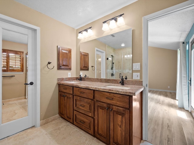 full bath featuring double vanity, a sink, baseboards, and a shower stall