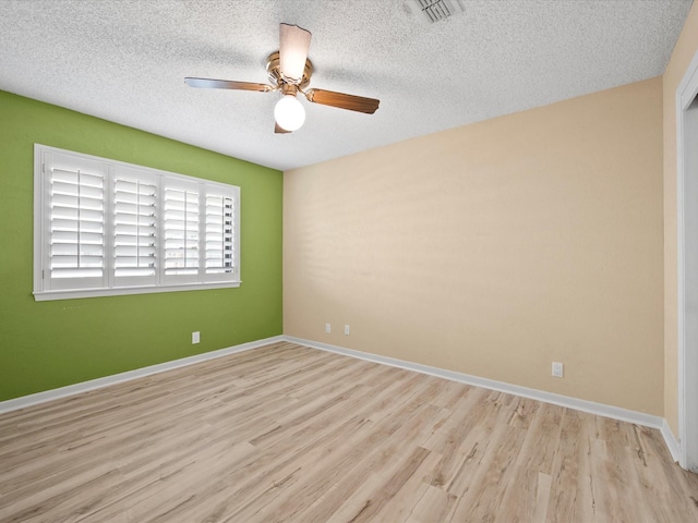 empty room with visible vents, wood finished floors, baseboards, ceiling fan, and a textured ceiling