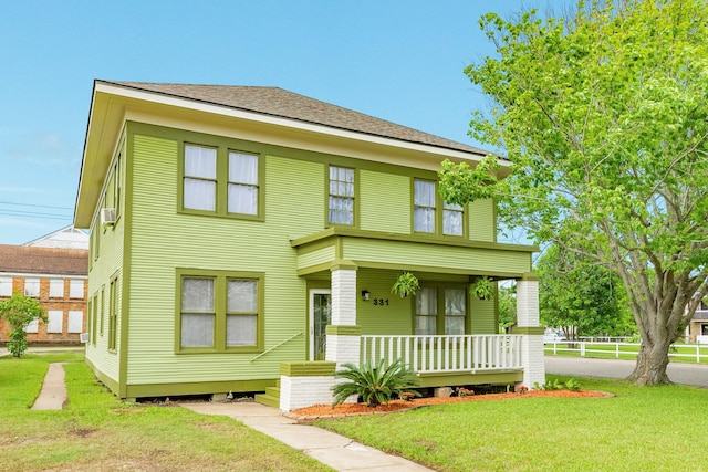view of front of home featuring roof with shingles, a porch, and a front lawn