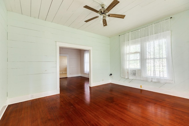 unfurnished room with wood ceiling, ceiling fan, baseboards, wood-type flooring, and wooden walls